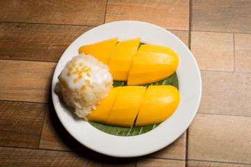 Mango and sticky rice in the white dish on wooden floor,Thai dessert popular in the summer of Thailand