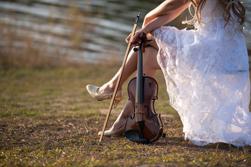 Young girl with hat playing the violin at lake.