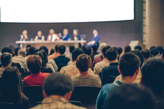 Rear view of Audience in the conference hall or seminar meeting which have Speakers are Brainstorming and talking on the stage, business and education about investment concept