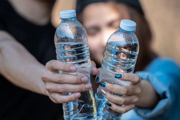 Couple of young people holding drinking water bottle on nature background.