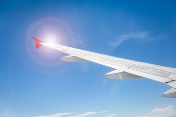 Wing of the plane on blue sky with sunlight. travel concept