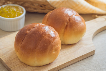 Round bun, bread rolls on wooden plate and pineapple jam