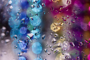 Multi color defocused macro abstract of water droplets on glass surface with illuminated background bokeh