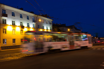 Fototapeta premium The motion of a blurred tram down the street in the evening.