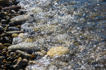 sea pebble beach with multicoloured stones, waves with foam