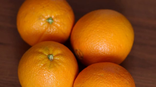 Four ripe juicy oranges on a brown wooden surface. Close-up. High resolution.