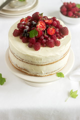 Summer home biscuit cake with curd cream, decorated with fresh berries of strawberries, raspberries and currants.