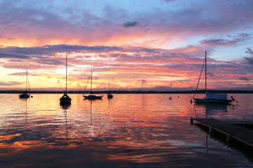 Beautiful summer evening nature background. Amazing summer evening landscape with group of drifting yachts on a lake Mendota during spectacular sunset. Bright sky reflects in the lake water.