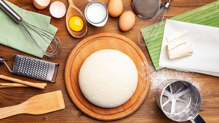 Concept for bakery, restaurant, cafe, production. Hands working with dough on a wooden table. Next to the companions, milk, flour, eggs. home made bread, pizza pasta, pies, cakes. copy space, top view