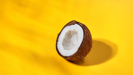 Ripe half of coconut on a yellow background. Creative food layout