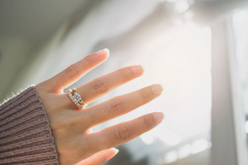 Close up of elegant diamond ring on woman finger with dark pink sweater winter clothe and sunlight...