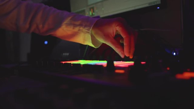 Music producer turning knobs in dark room