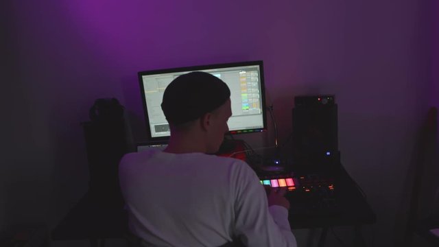 Music producer making music in dark room.