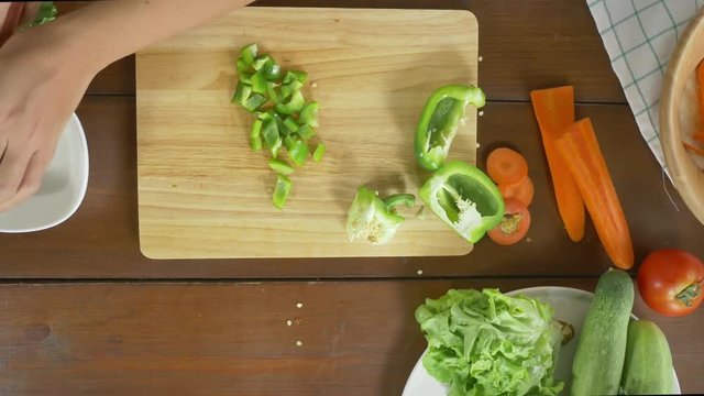 Top view of woman chief making salad healthy food and chopping bell pepper on cutting board in the kitchen.