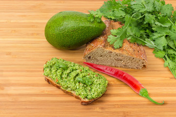Open sandwich with guacamole and some ingredients for its preparation