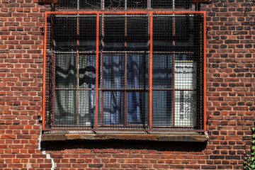 Verrostetes Fenstergitter an Backsteinhaus