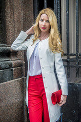 Fashionable young blonde in a spring fashionable suit and with a shopping bag in the center of Moscow
