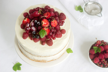 Summer home biscuit cake with curd cream, decorated with fresh berries of strawberries, raspberries and currants.