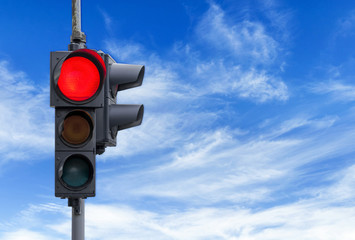 Red semaphore light with cloudy sky background