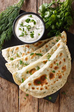 Delicious organic flat bread qutab stuffed with herbs served with yogurt close-up. Azerbaijani cuisine. Vertical top view