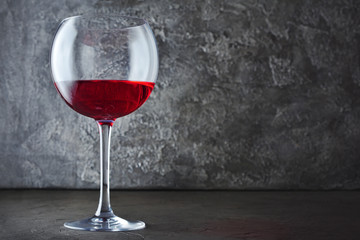 Single glass of red wine for tasting in dark cellar with copy space