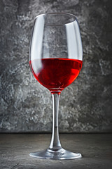 Single glass with red wine for tasting in dark cellar
