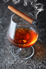 Strong alcoholic drink cognac in sniffer glass with smoking cigar