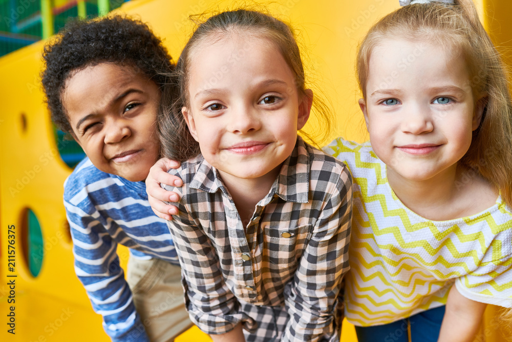 Wall mural colorful portrait of three happy kids posing looking at camera while having fun playing in children 