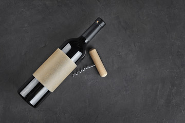 Flat lay of lying red wine bottle with empty label and corkscrew for tasting