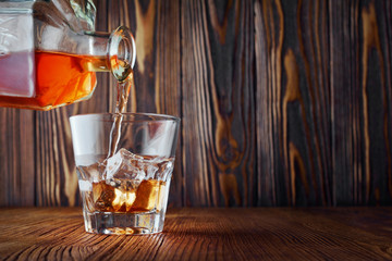 Strong alcoholic drink scotch whisky pour from decanter in old fashion glass with ice cube