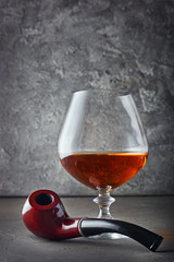 Strong alcoholic drink cognac in sniffer glass for tasting and smoking or tobacco pipe