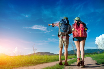 Asian couple is camping and walking along the road into the forest on weekend, Travel relaxing and adventure concept.