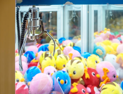 A mechanical arm selecting a random colorful dolls in a Claw capture device vending machine.