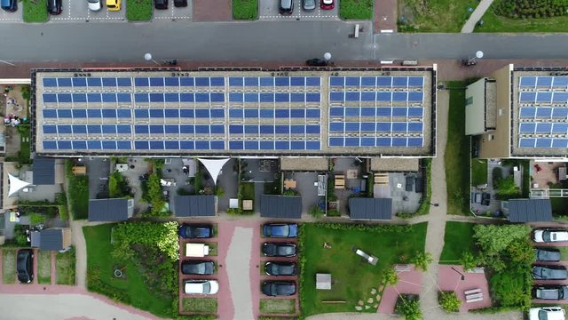 Aerial top down view of newly built apartment complex with photovoltaic solar panels installed they absorb sunlight as source of energy to generate electricity in this residential application 4k