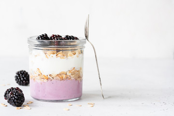 Yogurt parfait with blackberries and granola in a jar. Healthy breakfast, overnight oats or snack. Copy space for text - obrazy, fototapety, plakaty