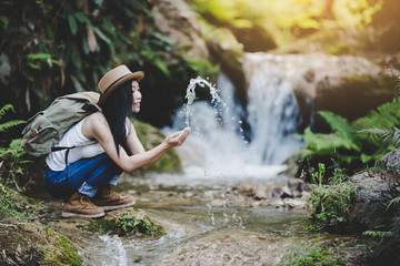 Young hiking lady washing her hands in the fresh cool water of a mountain stream.