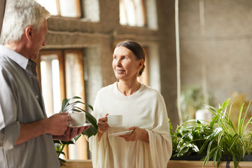 Mature couple having tea or coffee while talking and having rest in cafe