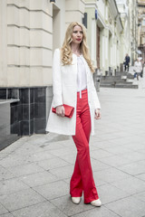 Fashionable young blonde in a spring fashionable suit and with a shopping bag in the center of Moscow
