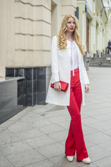 Fashionable young blonde in a spring fashionable suit and with a shopping bag in the center of Moscow
