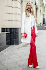Fashionable young blonde in a spring fashionable suit and with a shopping bag in the center of Moscow
