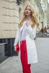 Fashionable young blonde in a spring fashionable suit and with a shopping bag in the center of Moscow
