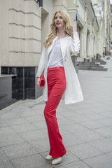 Fashionable young blonde in a spring fashionable suit and with a shopping bag in the center of Moscow
