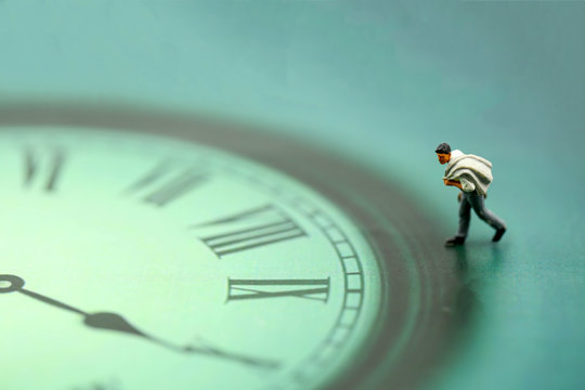 Miniature people : business man looking at watch and walk on the clock background, time business concept.