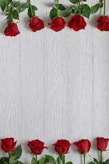 Frame of red roses on white wooden background. With space for text