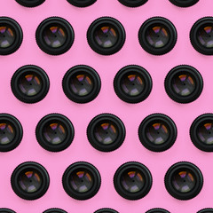 A few camera lenses with a closed aperture lie on texture background of fashion pastel pink color...