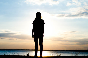 Sad woman standing on the road with sunset background.
