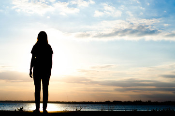 Sad woman standing on the road with sunset background.