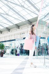 Naklejka premium Casual young woman with bags standing by one of window displays of department store