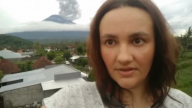 woman making selfie on cell phone, agung Volcano erupting january 2018
