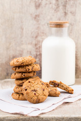 Chocolate oatmeal chip cookies with milk on the rustic wooden table.